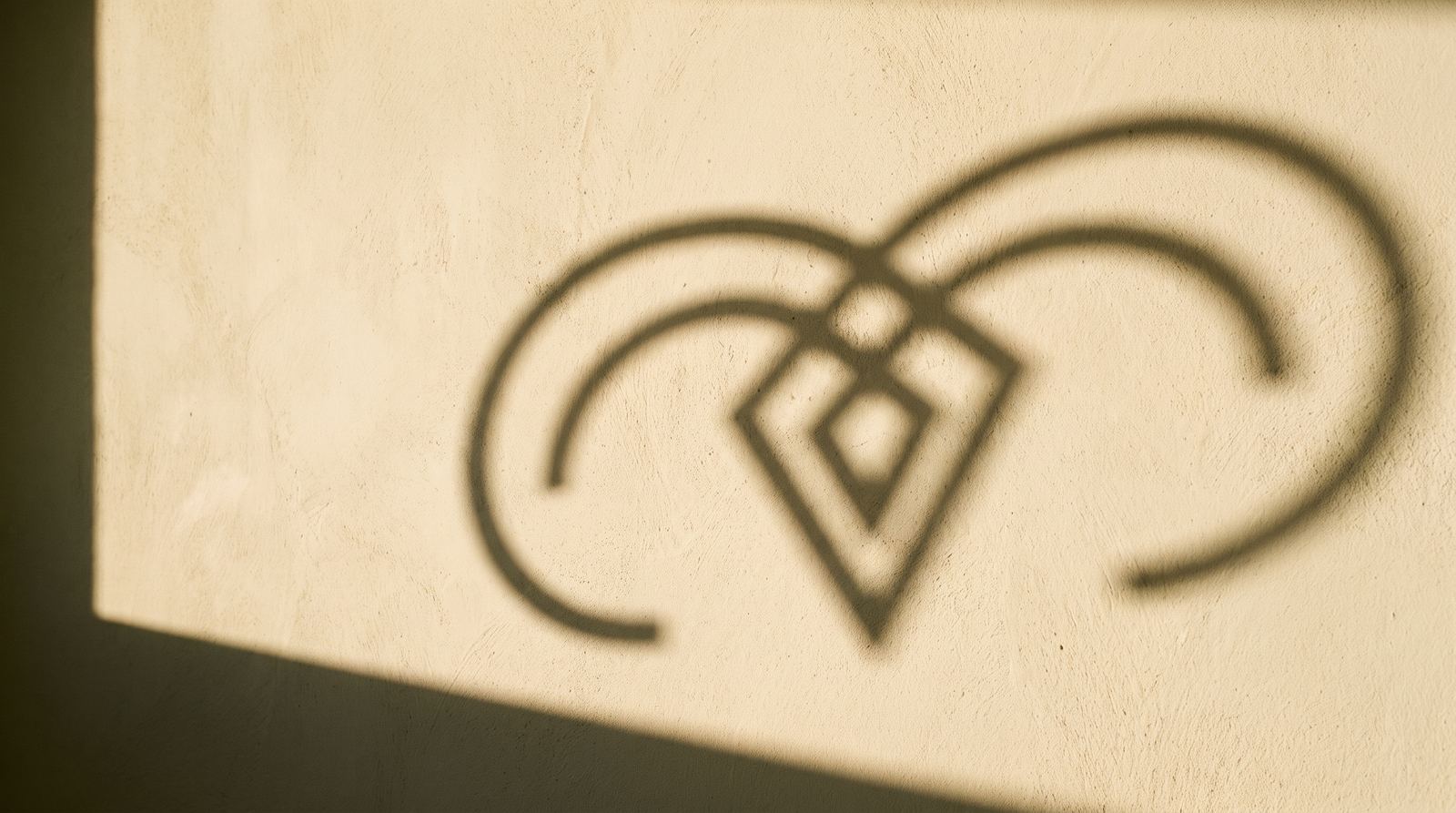 The Arkalis mark cast in sunlight on a wall